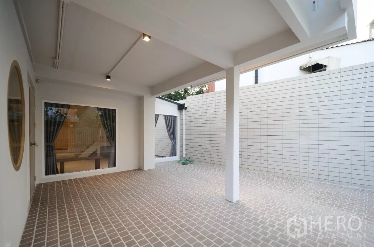 Townhouse for rent or sale in Watthana, Bangkok - Shaded patio and private walled courtyard with picture windows and outdoor lighting.