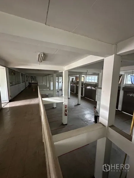 Shophouse for rent in Khlong Toei, Bangkok - View from the mezzanine across a high-ceiling shop floor with columns, windows and shuttered bays.