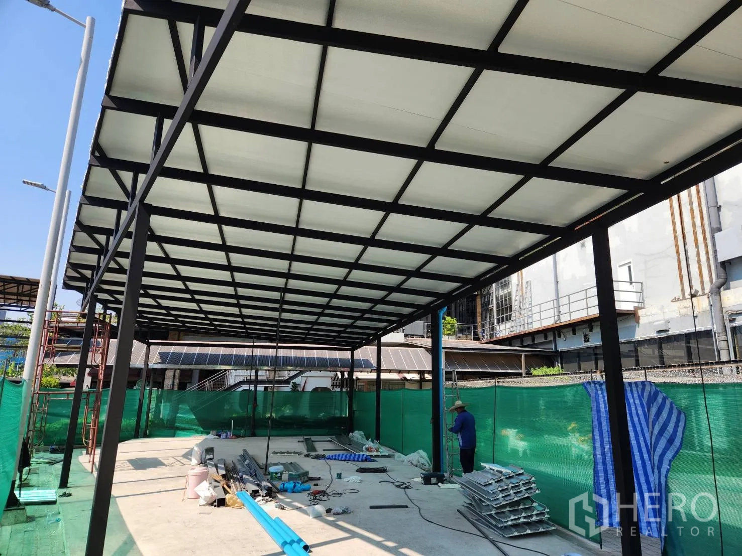 Retail Space for rent in Khlong Toei, Bangkok - Covered retail bay with black steel columns and clear-span roof, materials on the concrete slab in an urban setting.