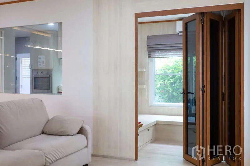 Detached House for rent or sale in Prawet, Bangkok - Cozy sitting area opening to a folding-glass sunroom with garden view.