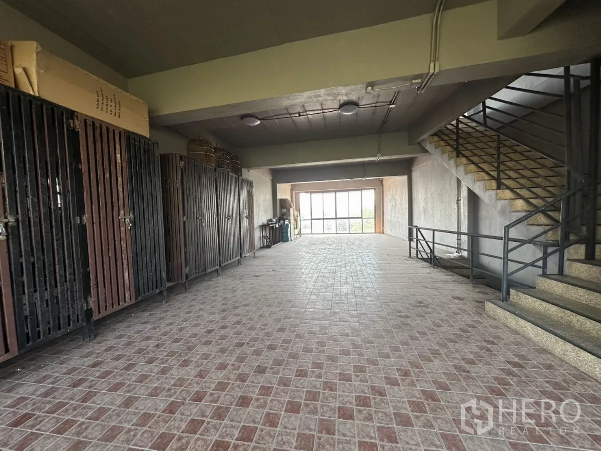 Shophouse for rent in Bang Na, Bangkok - Deep floor plate with lockers on one side and a staircase leading to upper levels.