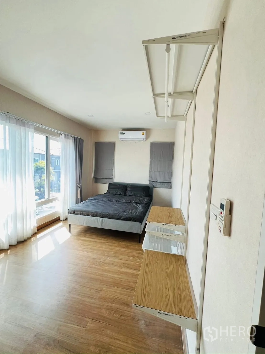 Detached House for rent in Prawet, Bangkok - Sunlit bedroom with double bed, large windows, sheer curtains and wood floors.