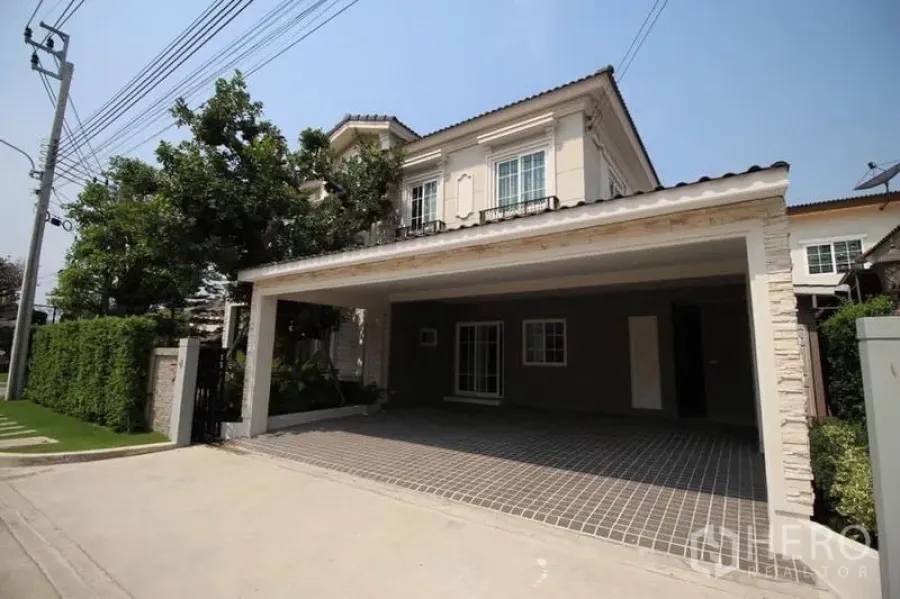 Detached House for rent or sale in Lat Phrao, Bangkok - Two-storey detached house with a covered two-car carport and hedge fence on a quiet street.