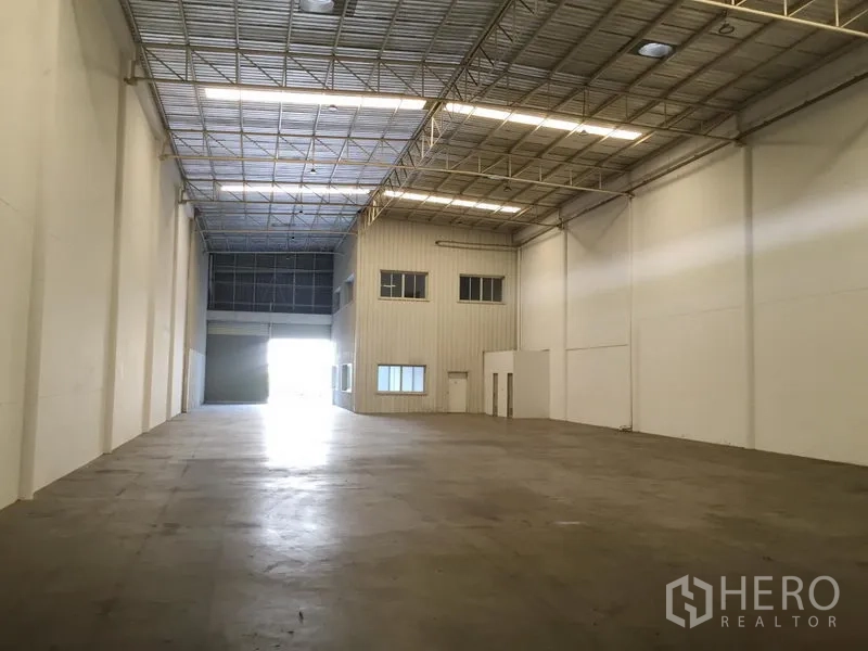 Factory for rent in Khlong Luang, Pathum Thani - Expansive clear-span production space with high ceiling, concrete floor and rear office block with shutter entry.