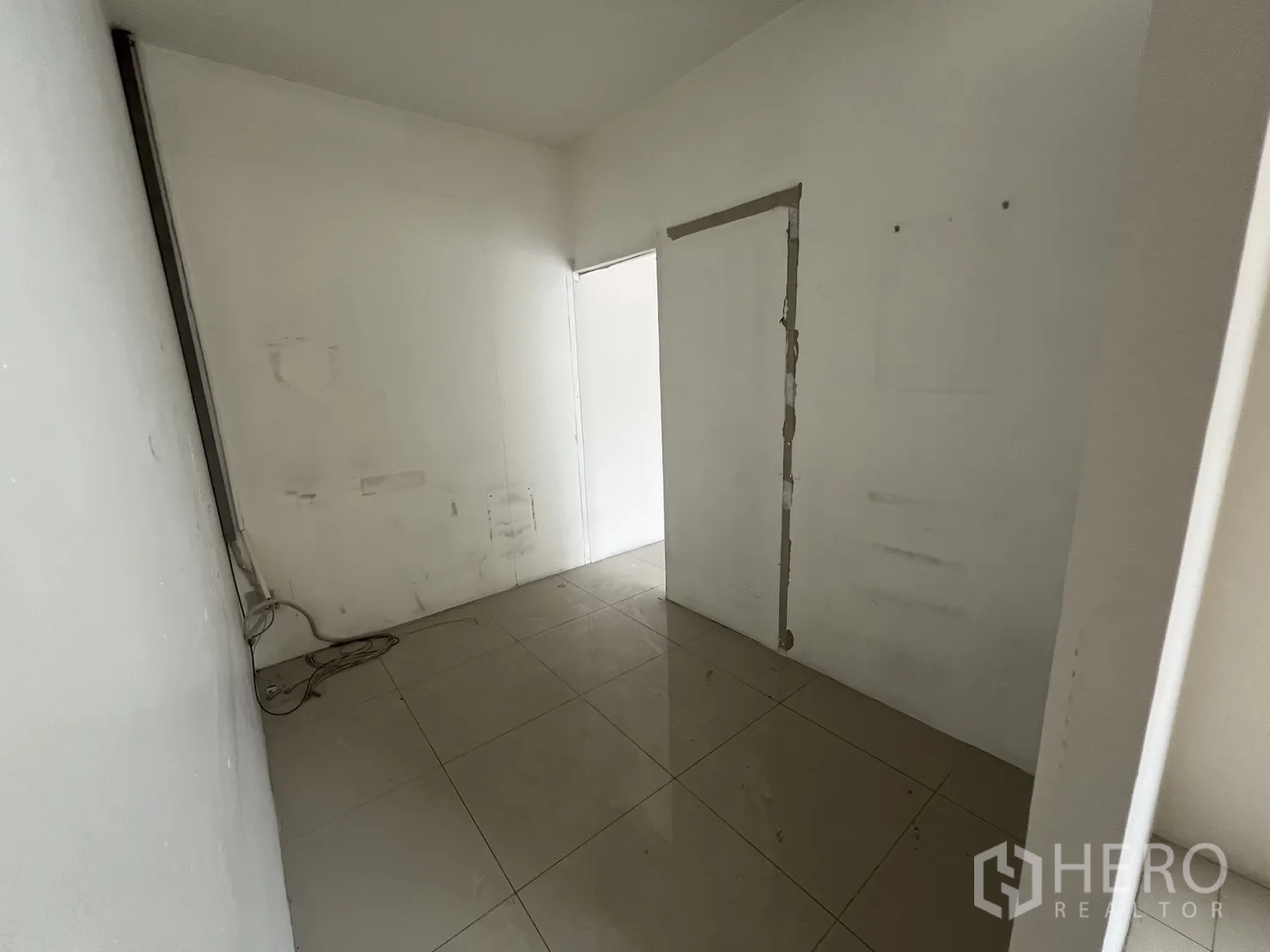 Retail Space for rent in Khlong Toei, Bangkok - Hallway nook with glossy tile flooring and patched white walls.