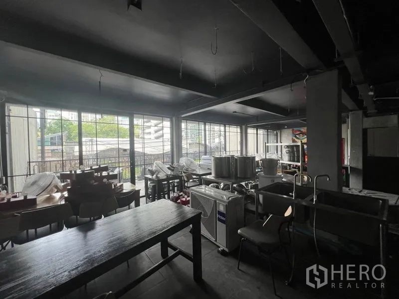Retail Space for rent in Watthana, Bangkok - Interior view toward full-height windows with equipment stored in the space.