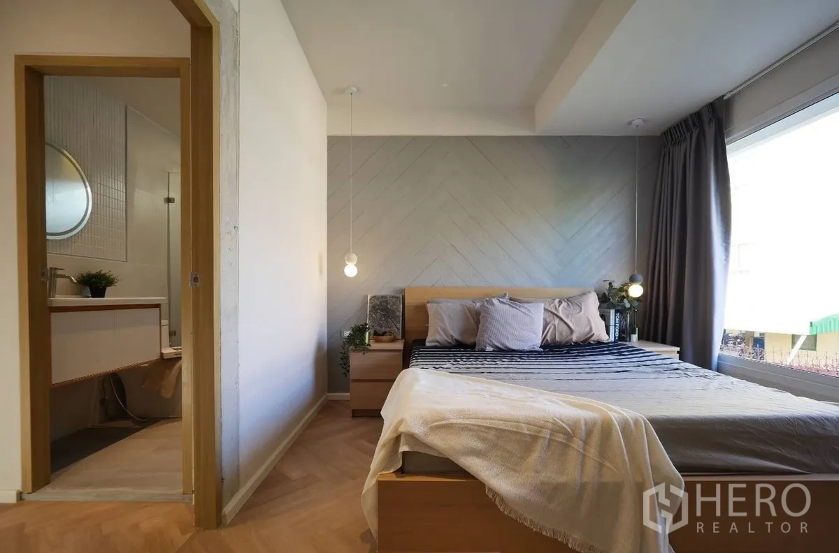 Townhouse for rent or sale in Watthana, Bangkok - Bedroom with chevron accent wall, large window and ensuite bathroom.