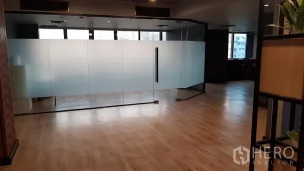 Office Space for rent in Khlong Toei, Bangkok - Glass-walled meeting room with frosted panels opening to a spacious wood-floored workspace.