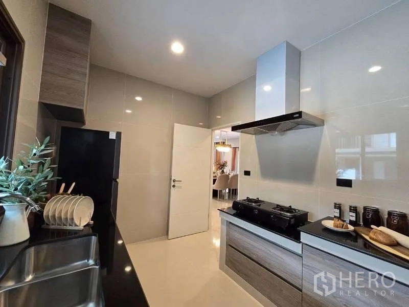 Detached House for rent in Bang Kapi, Bangkok - Kitchen cooking line with gas hob, hood and glossy tiled walls.