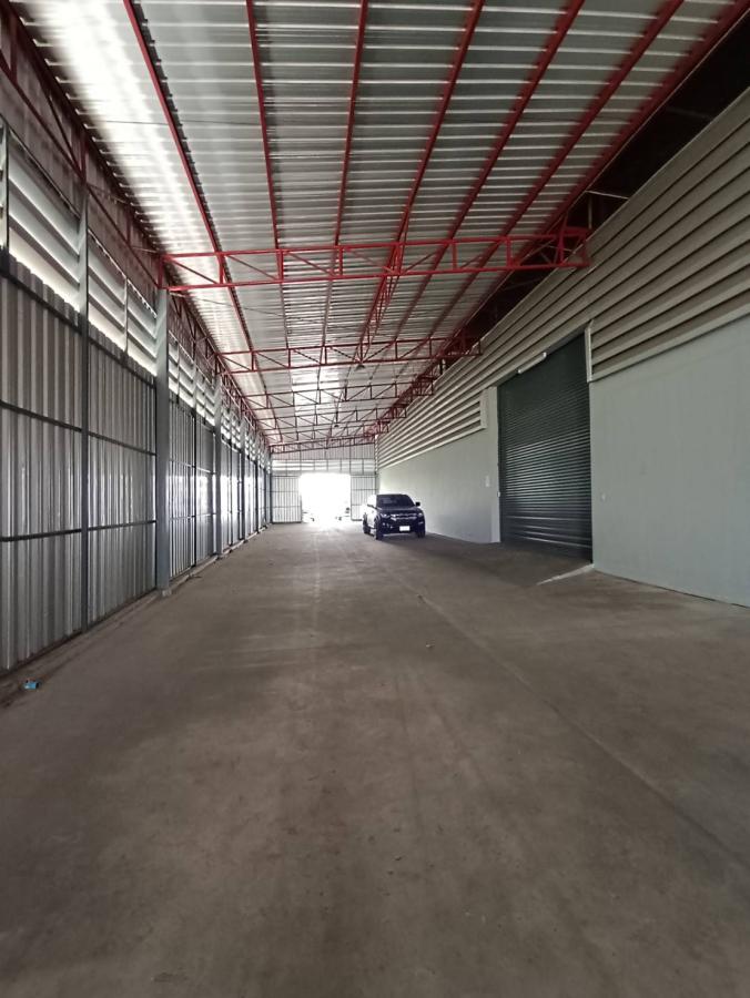 Warehouse for rent in Lat Krabang, Bangkok - Covered loading corridor with steel roof, red trusses and roller shutters for truck access.