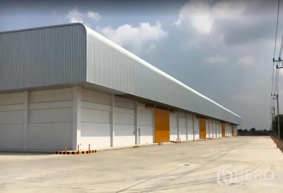 Warehouse for rent in Phra Nakhon Si Ayutthaya - Modern warehouse exterior with multiple loading bays and a wide concrete truck yard.