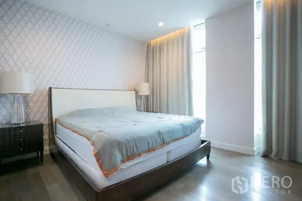 Condominium for rent or sale in Pathum Wan, Bangkok - Master bedroom with king bed, patterned feature wall and floor-to-ceiling curtains.