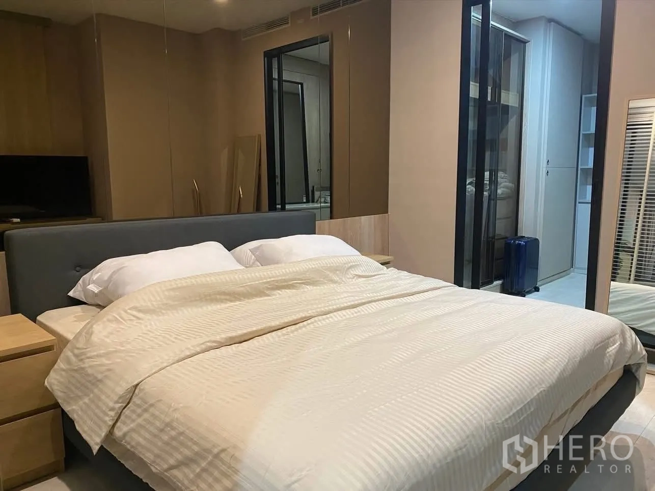 Condominium for rent in Pathum Wan, Bangkok - Primary bedroom with upholstered bed, mirrored wardrobes, and access to a walk-in closet.