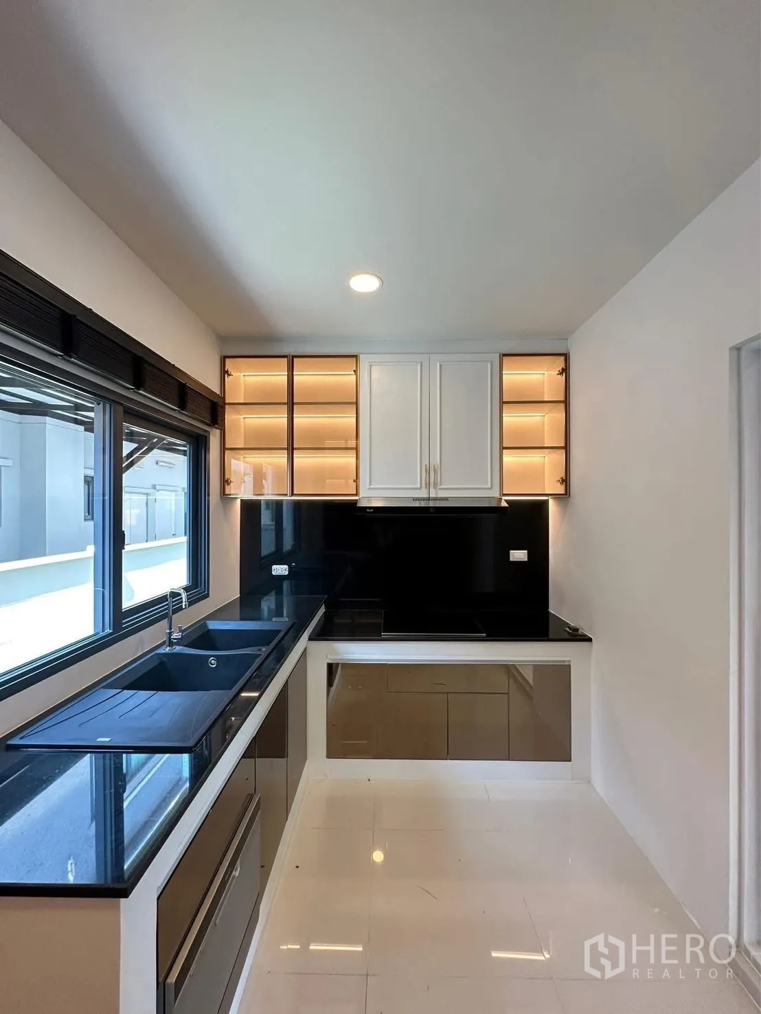 Detached House for rent in Bang Phli, Samut Prakan - Modern L-shaped kitchen with black stone countertops, sink, and lighted upper cabinets.