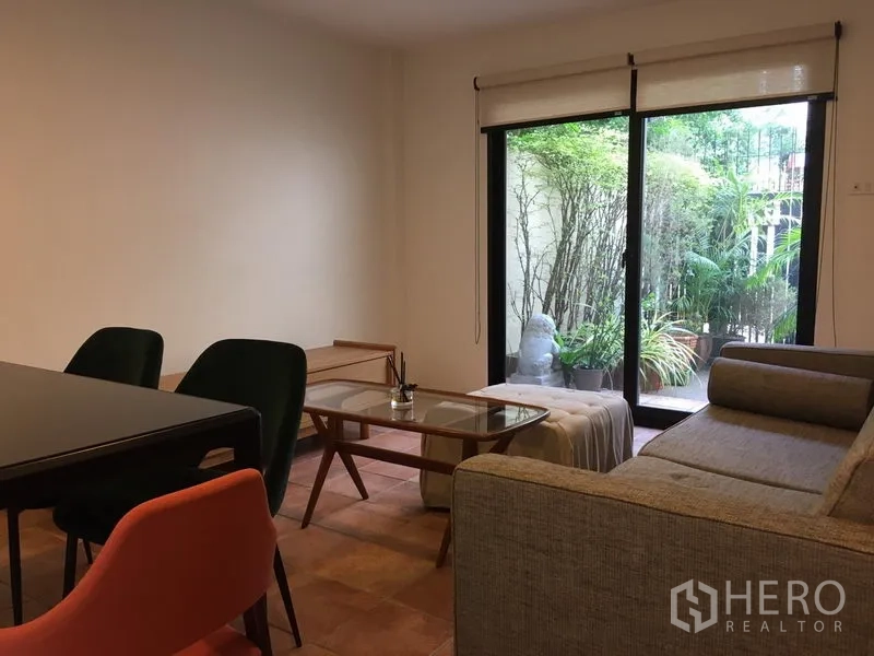 联排别墅 出租在Khlong Toei, Bangkok - 客厅落地滑门通向绿意庭院露台。