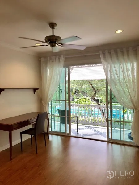 Detached House for rent in Mueang Samut Prakan, Samut Prakan - Work area with desk and sliding doors to a leafy balcony view providing natural light.
