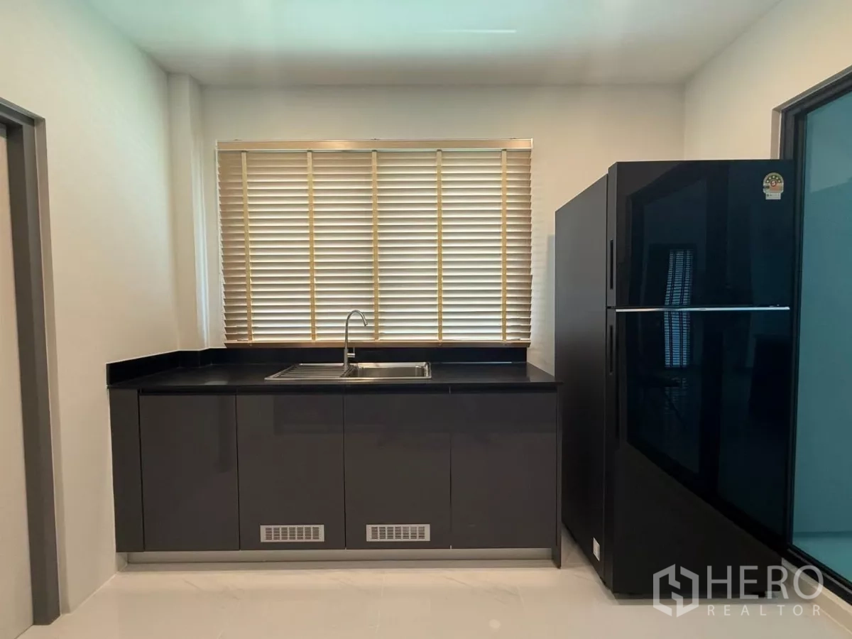 Detached House for rent in Bang Phli, Samut Prakan - Enclosed Thai kitchen with black countertop, sink and large refrigerator.