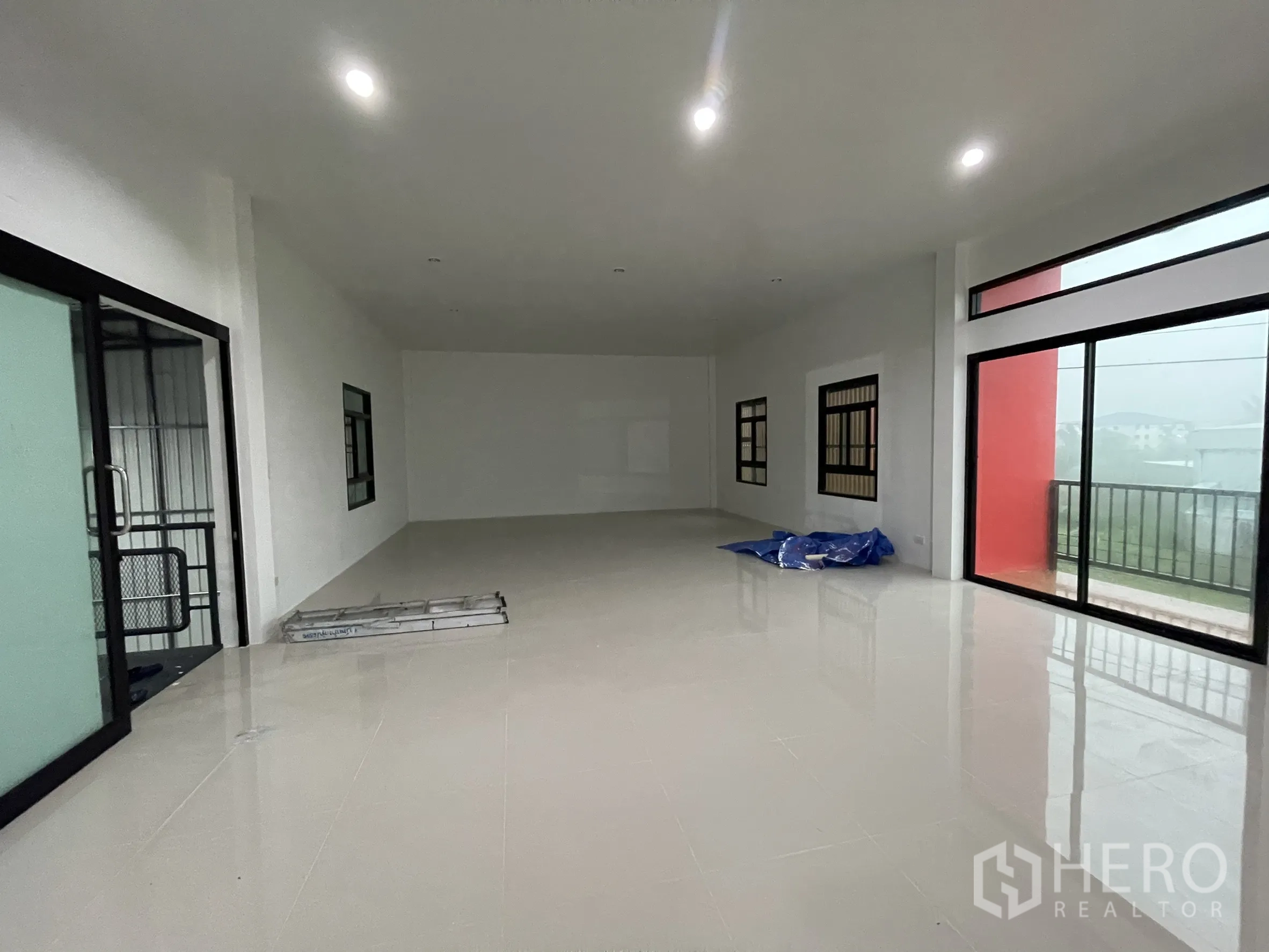 Factory for rent or sale in Lam Luk Ka, Pathum Thani - Spacious office level with wide glazing and balcony access overlooking the site.