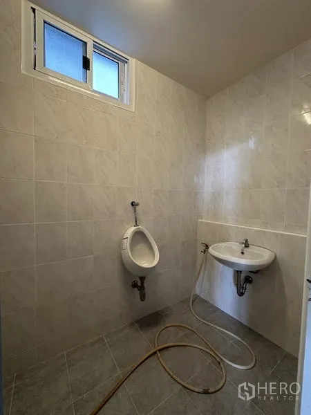 Warehouse for rent in Bang Kapi, Bangkok - Clean tiled restroom with window, urinal and wall‑mounted sink inside the facility.