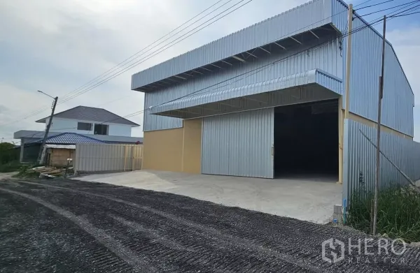 Warehouse for rent in Lat Krabang, Bangkok - Front entrance of the warehouse with large sliding doors and a concrete driveway.