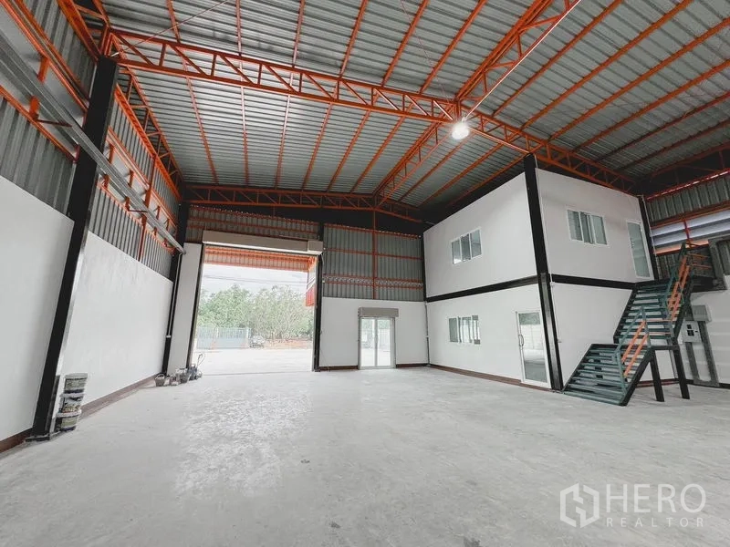 Warehouse for rent or sale in Khlong Luang, Pathum Thani - Deep interior view of the open-plan warehouse with high roller door, skylights and concrete floor.