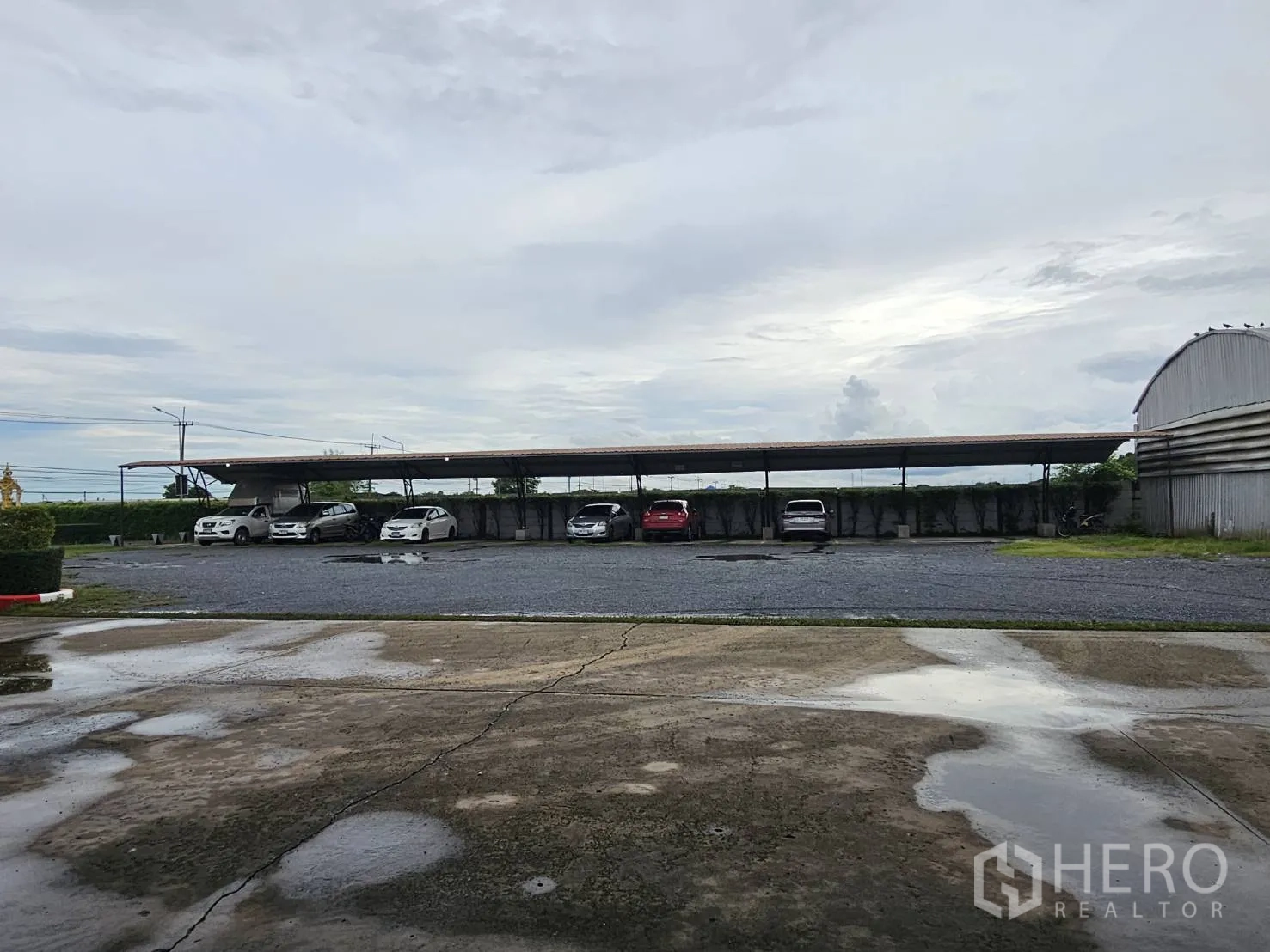 Warehouse for rent in Lam Luk Ka, Pathum Thani - Covered carport with multiple parking bays on gravel surface.