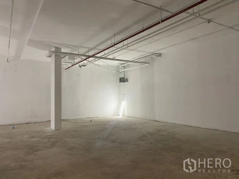 Retail Space for rent - Open‑plan retail floor with high ceiling, exposed services and a central column.