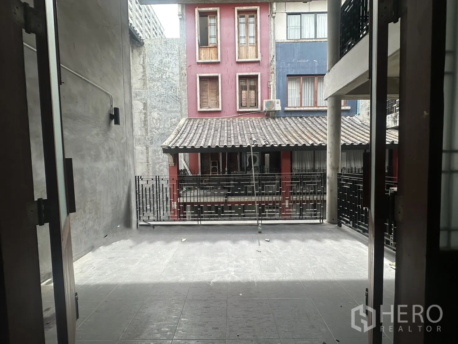 Home Office for rent in Pathum Wan, Bangkok - Deep terrace between buildings with tiled floor and metal railing.