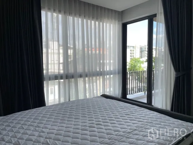 Detached House for rent in Watthana, Bangkok - Corner bedroom with floor-to-ceiling sheer curtains and balcony view.