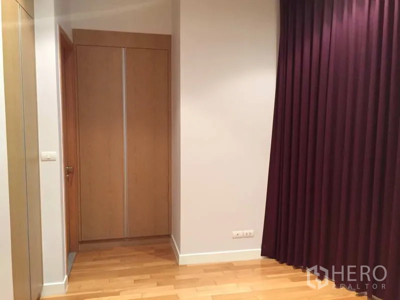 Condominium for sale in Khlong Toei, Bangkok - Bedroom entry with tall wardrobe, mirror and deep purple drapes.