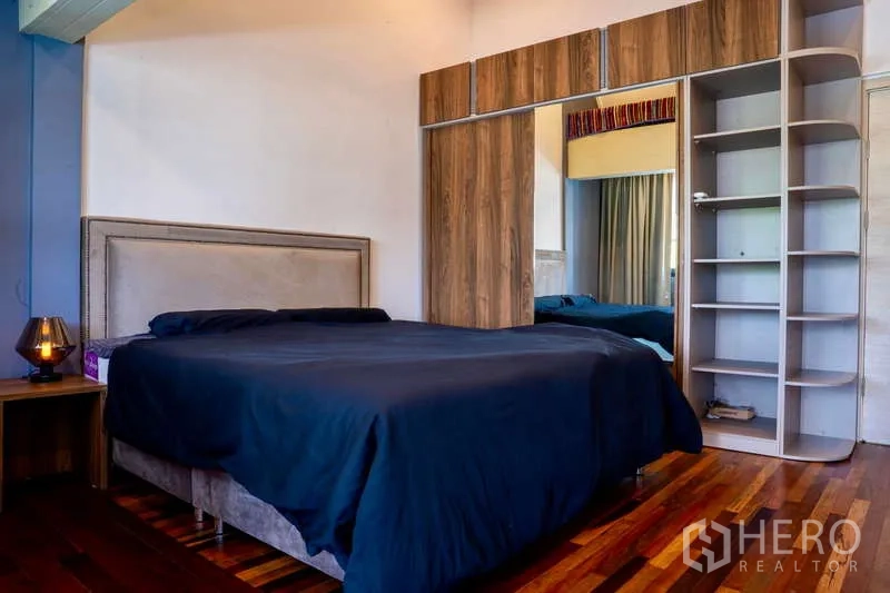 Townhouse for rent in Khlong Toei, Bangkok - Primary bedroom with large mirrored wardrobe and wooden flooring.