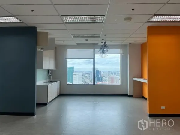 Office Space for rent in Chatuchak, Bangkok - Pantry and breakout space with kitchenette, orange accent wall and a wide window showcasing city views.
