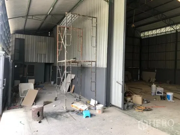 Warehouse for rent in Lam Luk Ka, Pathum Thani - Covered loading bay beside the warehouse with metal cladding, scaffolding and a wide sliding door.