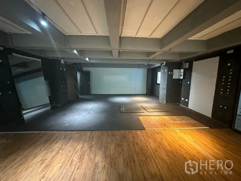 Office Space for rent in Bang Rak, Bangkok - Large studio-like area with dark feature walls, exposed ceiling beams, and mixed flooring zones.