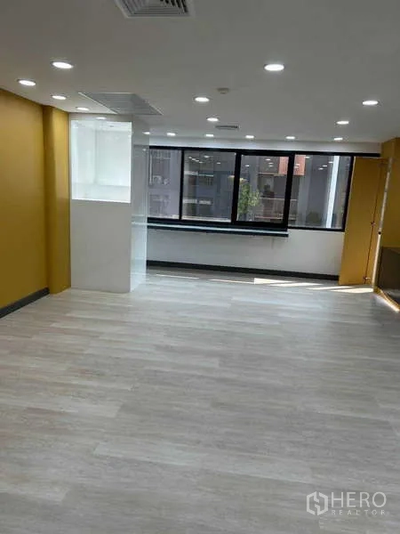 Office Space for rent in Khlong Toei, Bangkok - Open-plan workspace with yellow accent walls, wide windows and pale plank flooring.