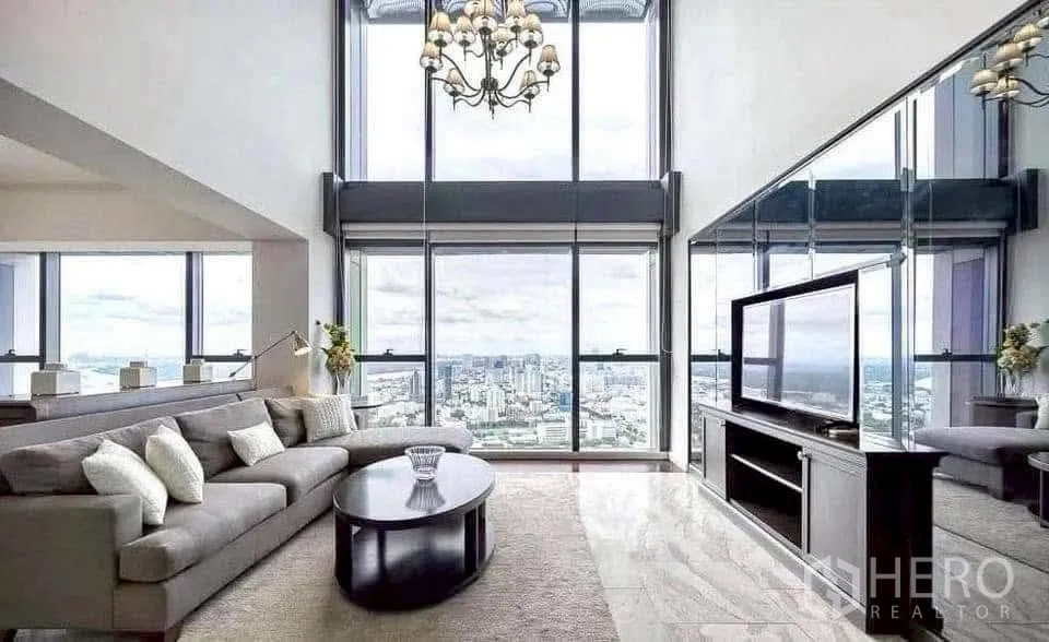 Condominium for rent in Sathon, Bangkok - Grand living space with chandelier, mirrored wall, TV console and towering windows framing the skyline.