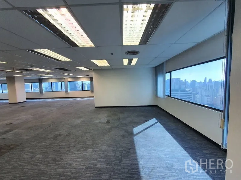 Office Space for rent in Watthana, Bangkok - Expansive open‑plan office with carpet tiles and wide windows showing the city skyline.