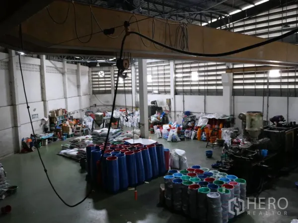 Factory for rent or sale in Bang Khun Thian, Bangkok - Production hall with high roof, plastic products on the floor and overhead crane cabling.