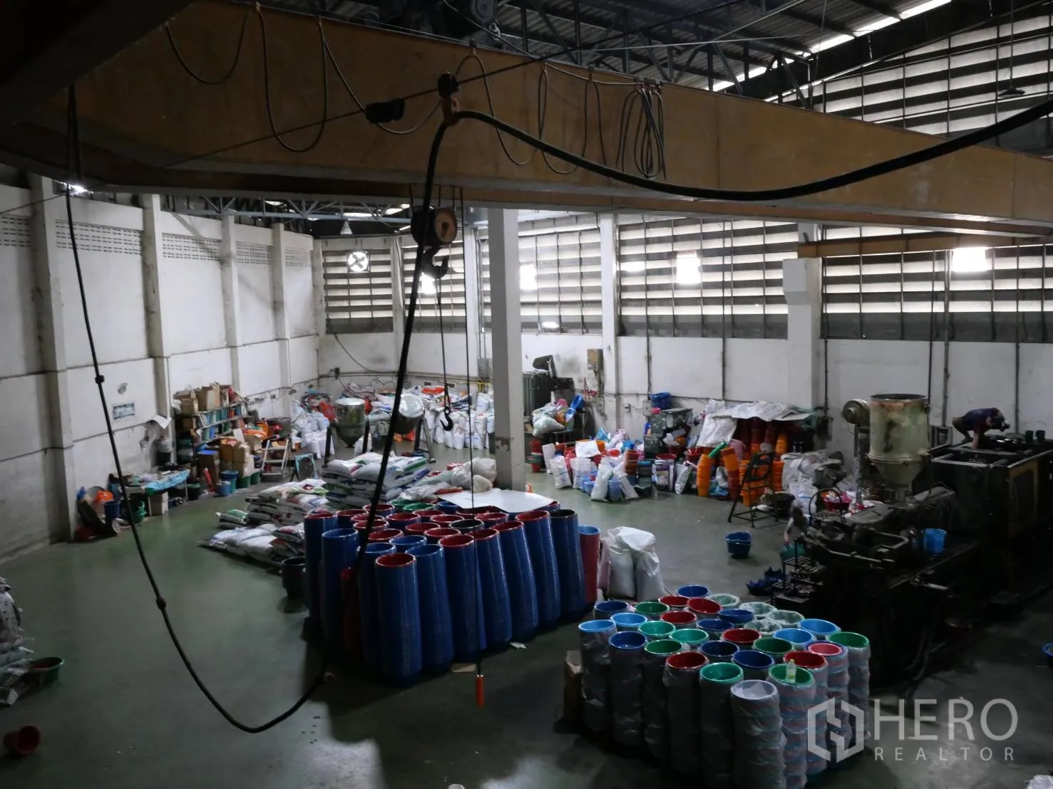 Factory for rent or sale in Bang Khun Thian, Bangkok - Production hall with high roof, plastic products on the floor and overhead crane cabling.