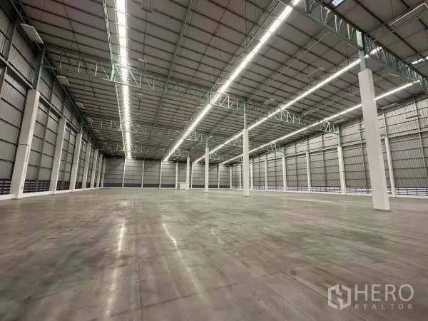 Factory for rent in Si Racha, Chon Buri - Spacious high-bay warehouse interior with LED strip lights, steel trusses and polished concrete floor.