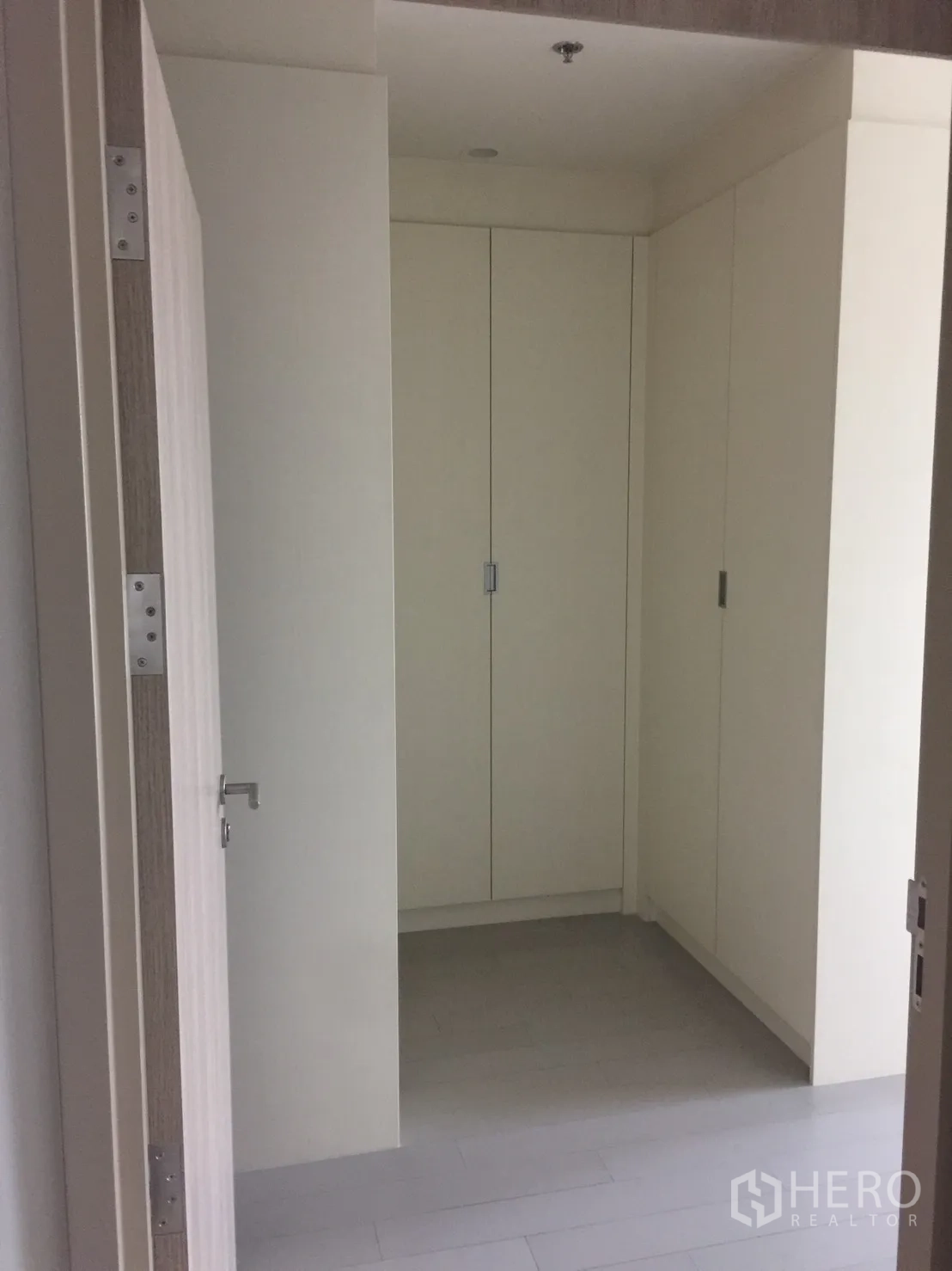 Condominium for rent in Pathum Wan, Bangkok - Hallway with built-in floor-to-ceiling wardrobes and light wood floors.