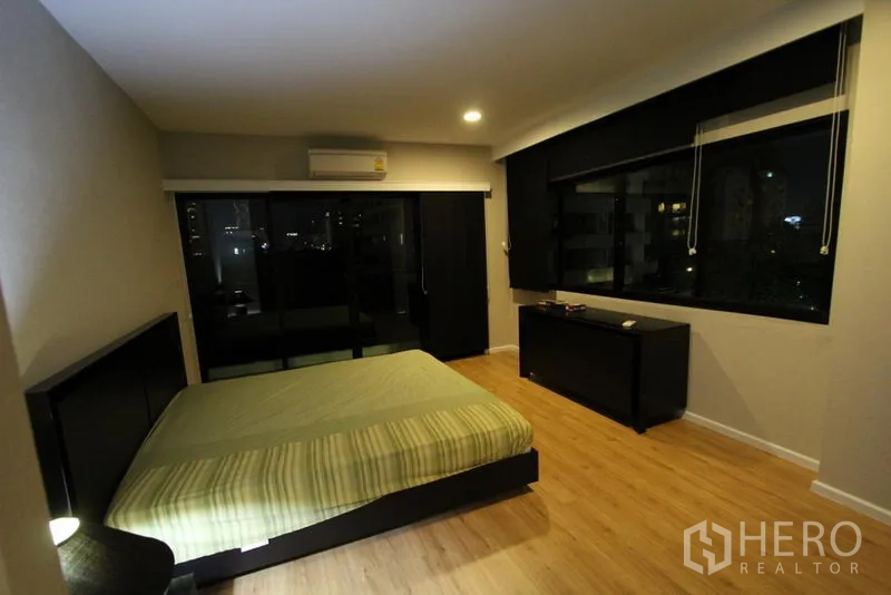 Condominium for rent in Pathum Wan, Bangkok - Second bedroom featuring large windows with city night view and blackout blinds.