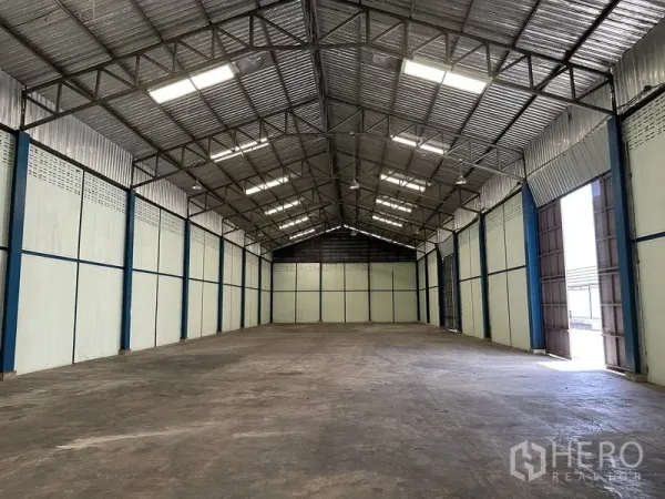 Warehouse for rent in Phra Nakhon Si Ayutthaya - Spacious warehouse interior with high steel truss roof, skylights, and durable concrete flooring.