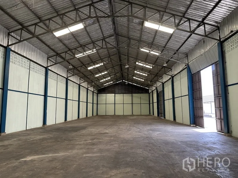 Warehouse for rent in Phra Nakhon Si Ayutthaya - Spacious warehouse interior with high steel truss roof, skylights, and durable concrete flooring.