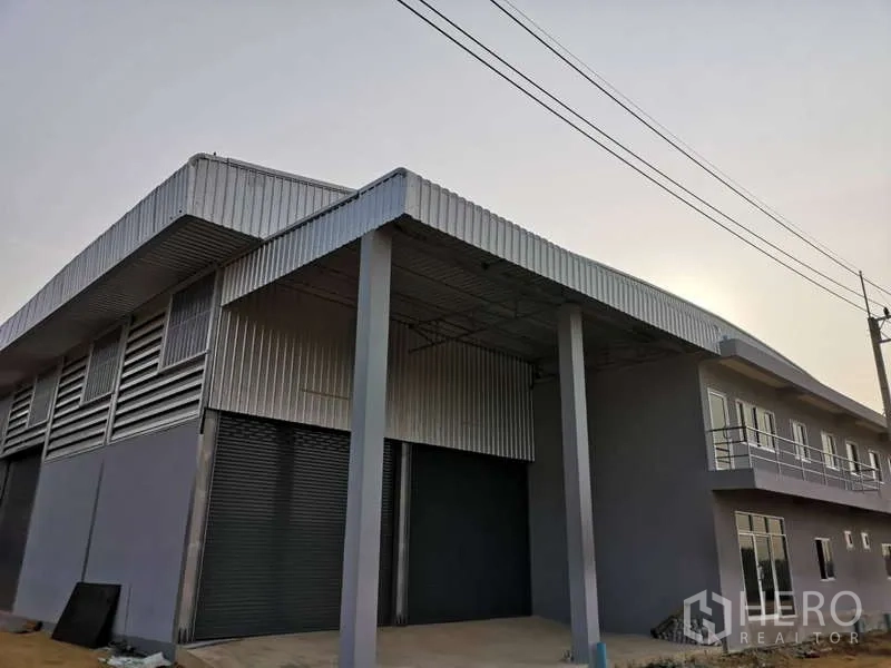 Warehouse for rent in Khlong Luang, Pathum Thani - Street-side view of the warehouse facade with canopy roof, power lines and dual roller doors.