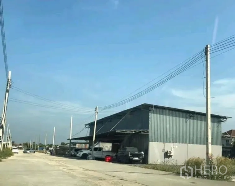 Warehouse for rent in Khlong Sam Wa, Bangkok - Street-side view of a steel-clad warehouse with covered loading bay and parking in Khlong Sam Wa, Bangkok.