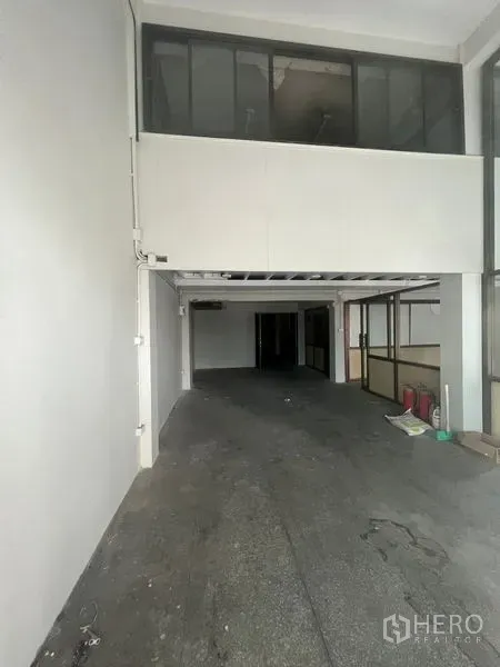 Shophouse for rent in Khlong Toei, Bangkok - Unfurnished shophouse hall with high ceiling, mezzanine, and side glass partitions ready for fit-out.