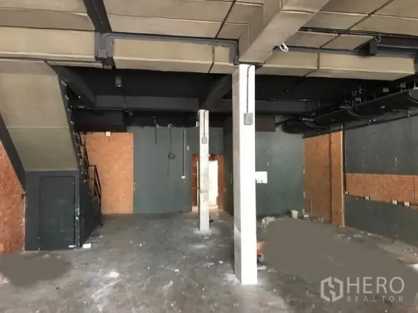 店屋 出租在Watthana, Bangkok - 一层室内挑高空间，外露管线与混凝土立柱，带内部楼梯。