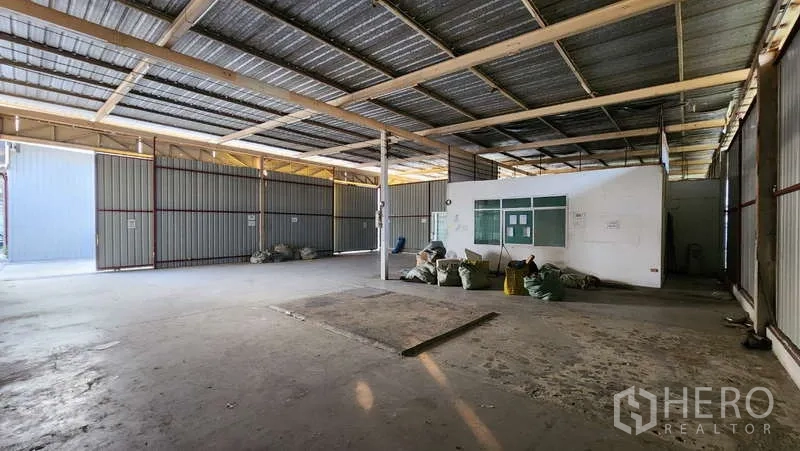 Warehouse for rent in Bang Khen, Bangkok - Open warehouse floor with a central column and attached office block.
