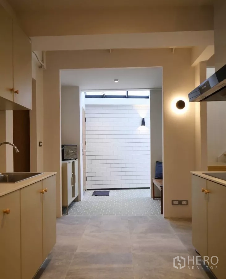 Townhouse for rent or sale in Watthana, Bangkok - Service area off the kitchen with white tiled wall and accent lighting.